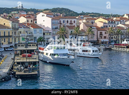 ISOLA LA MADDALENA, Sardinien, Italien - 7. MÄRZ 2019: kleine Fähre Hafen und Palmen gesäumten Strandpromenade Gebäude am 7. März 2019 in Isola La Maddalena, Sardinien, ICH Stockfoto