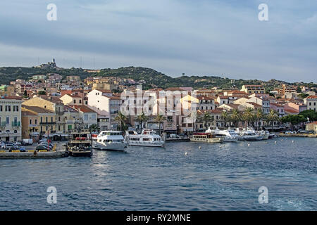 ISOLA LA MADDALENA, Sardinien, Italien - 7. MÄRZ 2019: kleine Fähre Hafen und Palmen gesäumten Strandpromenade Gebäude am 7. März 2019 in Isola La Maddalena, Sardinien, ICH Stockfoto