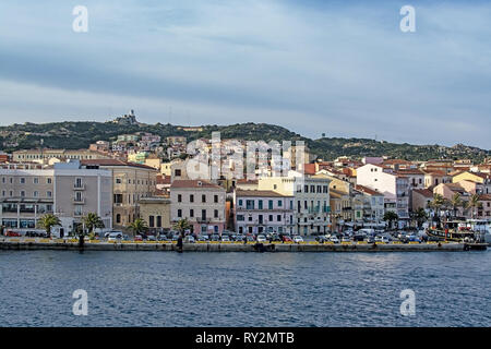 ISOLA LA MADDALENA, Sardinien, Italien - 7. MÄRZ 2019: kleine Fähre Hafen und Palmen gesäumten Strandpromenade Gebäude am 7. März 2019 in Isola La Maddalena, Sardinien, ICH Stockfoto