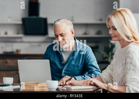 Selektiver Fokus der freundliche Mann sassen und am Laptop in der Nähe der attraktiven Blondine Frau Stockfoto