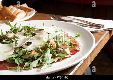 Italienisches carpaccio auf Tisch im Restaurant, mit Messer und Gabel Stockfoto