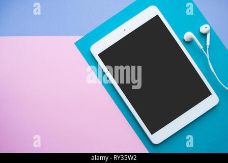 Flach der weiße Tablette und Kopfhörer in Blau, Lila und Rosa Hintergrund mit Copyspace. Stockfoto