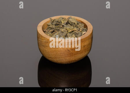 Viele Stücke von trockenen Grüner Tee mit Houten auf schwarzem Glas Stockfoto