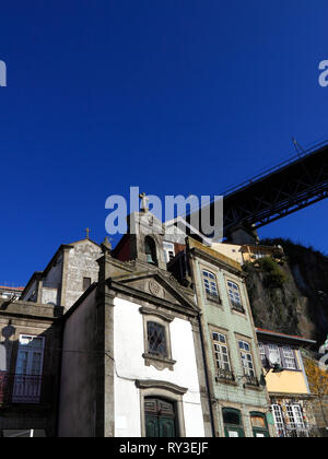 Einzelheiten über die interessante und vielfältige Architektur von Porto zu sehen, einer der berühmten und allgegenwärtigen Brücken über die Häuser, gegen seine Deep Blue sk Stockfoto