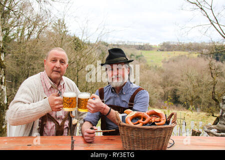 Zwei Männer tragen bayerische Oktoberfest bemühen, trinken Bier und Gefühl glücklich im Freien Stockfoto