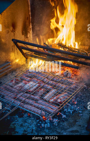 Eine Auswahl von Schweinefleisch Schnitte einschließlich Rippen, Würstchen und Schweinebauch auf einem Grill zubereitet. Hochformat. Stockfoto