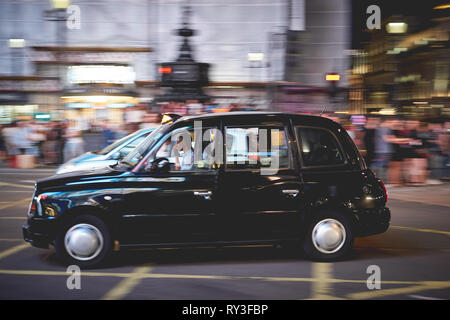 London, UK - August, 2018. Ein Taxi in Piccadilly Circus bei Nacht. Die schwarzen Taxis sind die meisten iconic Symbol von London sowie die roten Doppeldeckerbusse. Stockfoto