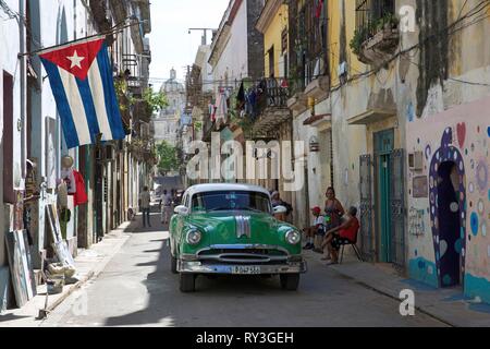 Kuba, Havanna, alte Habana, als Weltkulturerbe von der UNESCO, alte amerikanische Green Car in einer Gasse, wo eine kubanische Flagge schwimmt, mit der Place du Capitole im Hintergrund Stockfoto