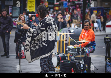 London, UK - August, 2018. Eine strasse Rock Musiker Durchführung außerhalb der Tottenham Court Road U-Bahnstation in einem überfüllten Oxford Street. Stockfoto