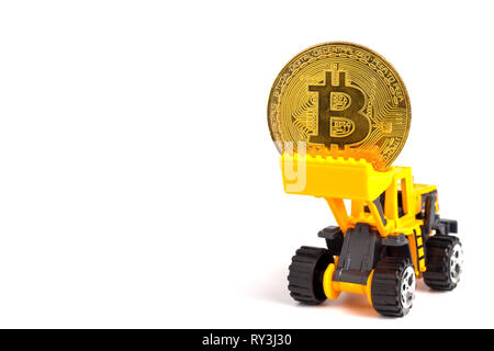 Close up gelb Traktor Modell hebt die goldenen Münzen. Das Konzept der Bitcoin Mining business. Stockfoto