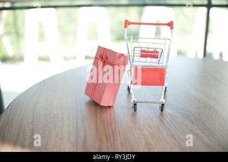 In der Nähe von roter Geschenkbox und Warenkorb auf Tisch für Shopping und e-commerce Konzept Stockfoto