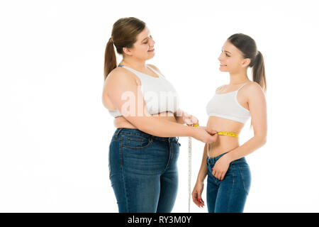 Happy übergewichtige Frau messen Taille schlanke Frau isoliert auf weiss Stockfoto