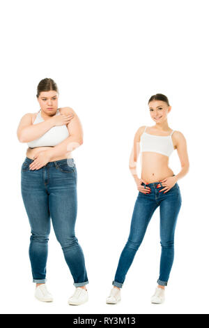 Traurig übergewichtige Frau, die Körper mit Händen, während schlanke Frau posiert auf weißem isoliert Stockfoto