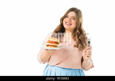 Glücklich lächelnde Frau mit leckeren Burger auf dem Teller und Gabel isoliert auf weißem Stockfoto