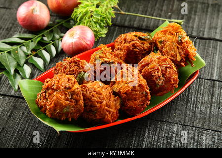 Indische Küche - knusprig gebratener onin Krapfen, Ulli Vada, pakkoda, pakora, berühmten indischen Street Food. Stockfoto