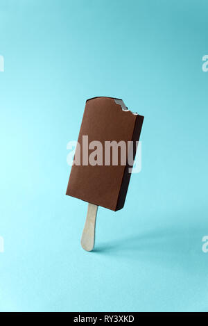 Papier gebissen Vanilleeis Popsicle mit Schokolade auf blauem Hintergrund abgedeckt. Kopieren Sie Platz. Kreative oder Kunst essen Konzept Stockfoto