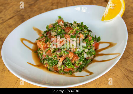 Salat Tabule. Mit Petersilie, Tomaten, roten Zwiebeln, manna Kruppe, Granatapfelsaft und frisch gepresste Zitrone. Stockfoto