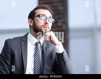 gut aussehend Geschäftsmann denkt, sitzen auf der Couch in seinem Büro Stockfoto