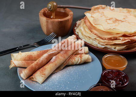 Pfannkuchen mit Beeren, Marmelade, Honig und Schokolade, bestreut mit Puderzucker und Zimt Stockfoto