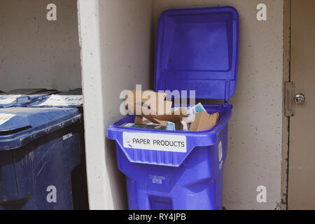 Mülltonnen sind mit Paketen, die mit dem Abfall auf der Straße vor dem Hintergrund der weißen Gebäude, niemand überfüllt. Stockfoto