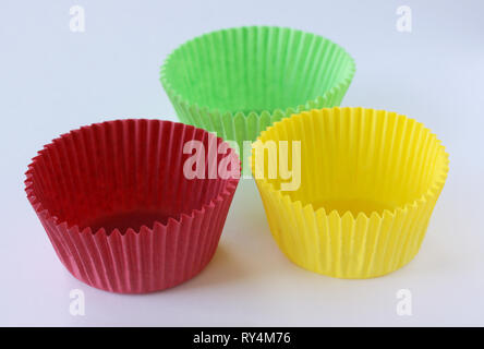 Bunte leere Formen Kapseln für Muffins und Cupcakes auf weißem Hintergrund - Backen Dessert - close up auf weißem Hintergrund Stockfoto