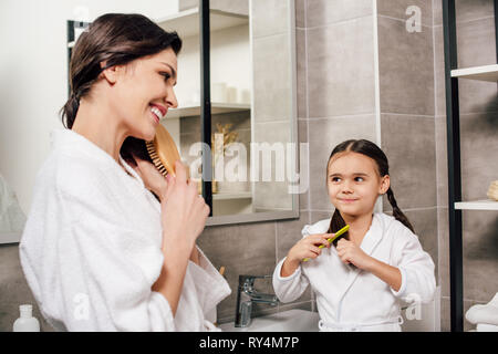 Mutter und Tochter In weißen Bademänteln Kämmen in Bad Stockfoto