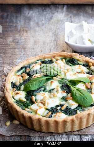 Vegetarische Spinat Tarte mit Feta und Pinienkernen auf hölzernen Tisch Stockfoto