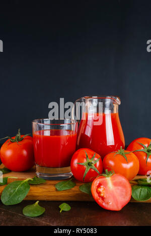 Glas frischen Tomaten-/Paradeisersaft und Tomaten auf einer hölzernen Schneidebrett Stockfoto