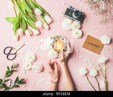 Weibliche Hände halten Kaffee, Blumen, Filmkamera und Zeichen glücklich Stockfoto