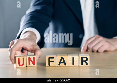 Business Mann legt in ersten zwei Buchstaben aus dem Wort unfair, so dass es gerecht wird; Sport oder Business fair play Konzept, blau getönt mit ligth flare Stockfoto