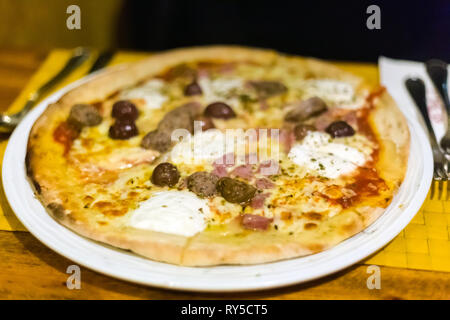 Traditionelle maltesische Pizza mit Wurst, Oliven und Käse aus Holz befeuerten Ofen in einem lokalen Restaurant serviert. Köstliche maltesische Küche Stockfoto