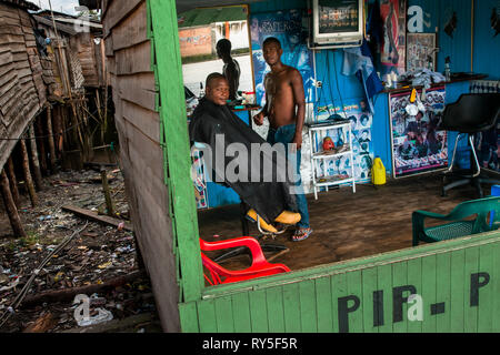 Eine kolumbianische Friseur schneidet die Haare eines Mannes in einem Friseur in einem Elendsviertel in Tumaco, Kolumbien. Stockfoto