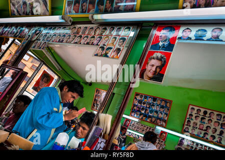 Eine junge BOLIVIANISCHE Friseur schneidet die Haare eines Kunden in einem Friseur in El Alto, Bolivien, 11. Februar 2014. Stockfoto