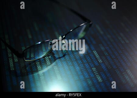 Lesen von Daten im digitalen Zeitalter. Gläser und fließende binären Code Matrix. geringe Tiefenschärfe Bild der Gläser auf Display. in mehreren Zeilen, blau Stockfoto