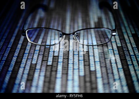 Lesen von Daten im digitalen Zeitalter. Gläser und fließende binären Code Matrix. geringe Tiefenschärfe Bild der Gläser auf Display. in mehreren Zeilen, blau Stockfoto