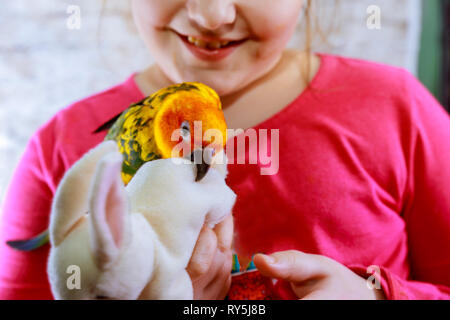 Wellenförmige Parrot neben ein kleines Mädchen. Kinder spielen gelb Green Parrot Stockfoto