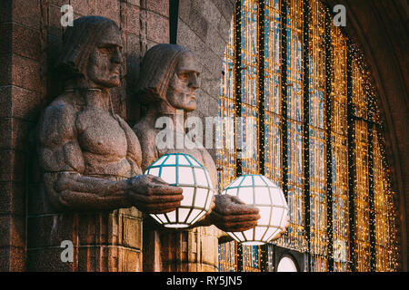 Helsinki, Finnland. Nacht Blick auf zwei Paare von Statuen, die die kugelförmige Lampen am Eingang nach Helsinki Hauptbahnhof. Am Abend oder in der Nacht Stockfoto