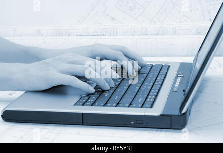 Weibliche Hände am Laptop Tastatur. Architektonische Pläne im Hintergrund. Blaue Tönung. Stockfoto