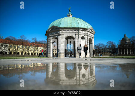 12. März 2019, Bayern, München: Zwei Frauen sind in einer Pfütze wider, wie sie hinter den Diana Tempel im Garten im Innenhof. Foto: Sina Schuldt/dpa Stockfoto