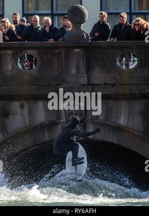 12. März 2019, Bayern, München: Passanten beobachten von einer Brücke ein Surfer auf die Welle der Eisbach. Foto: Peter Kneffel/dpa Stockfoto