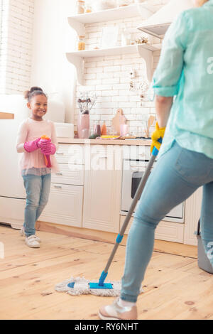 Cute strahlenden Mädchen an ihre Mutter wischen den Boden auf der Suche Stockfoto