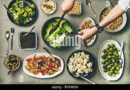 Gesunde vegetarische Gerichte in Platten und Frau Hände unter Salat Stockfoto