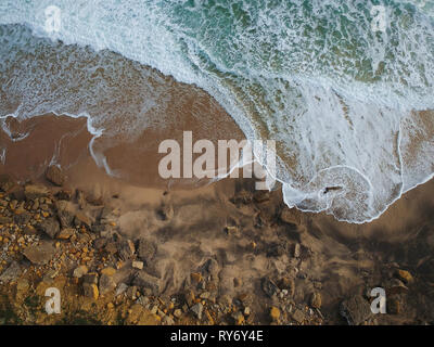 Luftaufnahme von Wellen und Felsen in einen Strand. Blaue Wasser Hintergrund Stockfoto