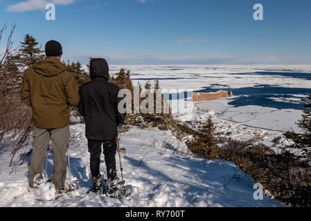 Vater und Sohn, die nach Ansicht der Percé Rock nach Schneeschuhwandern des Mount Sainte-Anne nach oben. Stockfoto