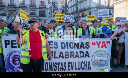 Eine Demonstrantin gesehen Parolen auf ein Megaphon vor den Demonstranten halten ein Banner und Plakate während der Demonstration. Die Gewerkschaften protestierten am Puerta del Sol in Madrid gegen Kürzungen bei den Renten sammeln Hunderte von Menschen. Stockfoto