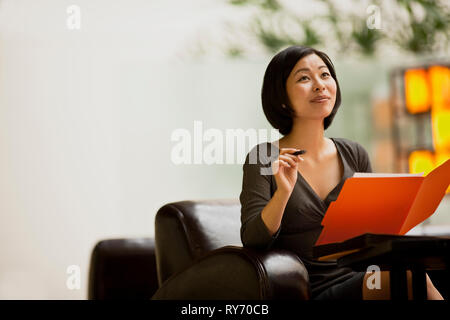 Frau sitzt in einer Lobby in einer Datei suchen. Stockfoto