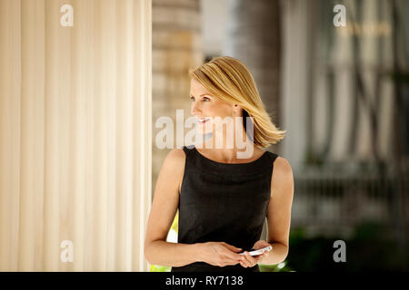 Geschäftsfrau stehen vor dem Hotel und Ihr Handy. Stockfoto