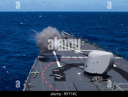 Der Arleigh-burke-Klasse geführte Anti-raketen-Zerstörer USS Curtis Wilbur (DDG54) Brände eine Markierung 45 5-inch Gun aus dem Vorschiff während einer Live-Fire Training während des Betriebs im philippinischen Meer, 10. März 2019. U.S. Navy Kriegsschiffe Zug zusammen die taktischen Kenntnisse, Letalität zu erhöhen und die Interoperabilität der teilnehmenden Einheiten in einer Zeit, in der Große-Wettbewerb. (U.S. Marine Foto von Mass Communication Specialist 1. Klasse Alexandra Seeley) Stockfoto