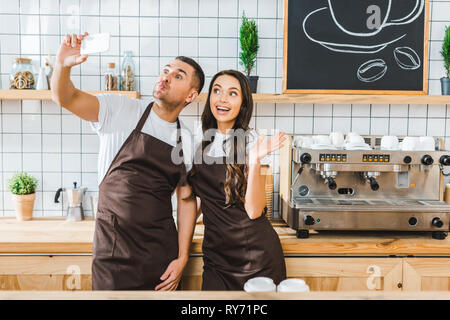 Kassierer in Braun Schürzen stehen und unter selfie in Coffee House Stockfoto