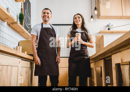 Kassierer und lächelnd hinter einem Tresen in Coffee House Stockfoto